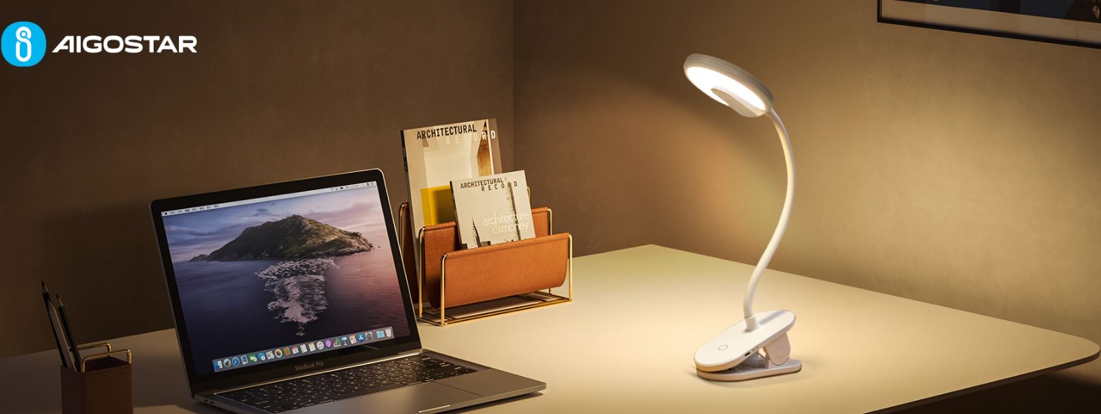 Ein weißer, aufgeräumter Schreibtisch auf dem ein Laptop ein Organizer und eine Schreibtischlampe stehen